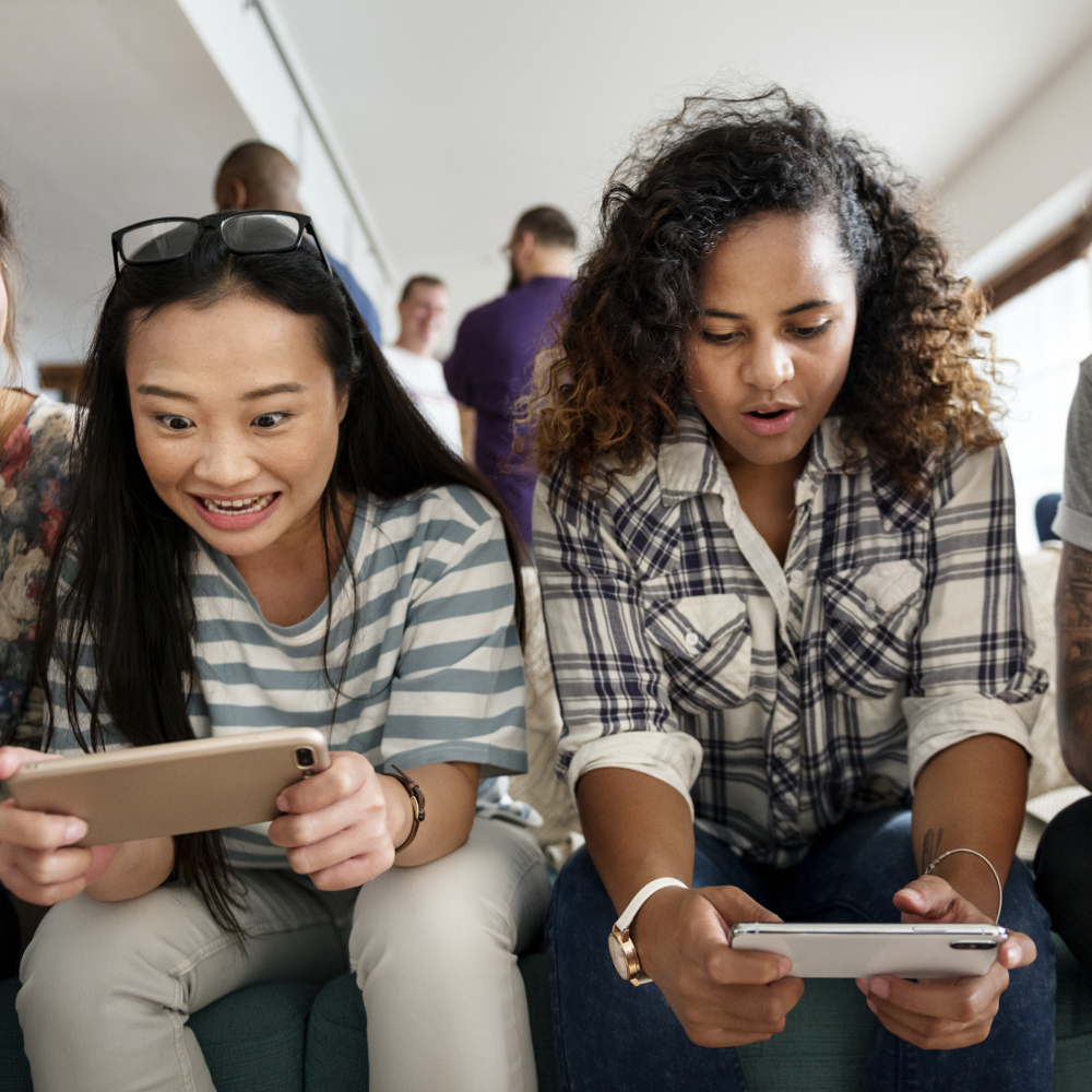Freunde spielen gemeinsam auf ihren Smartphones.
