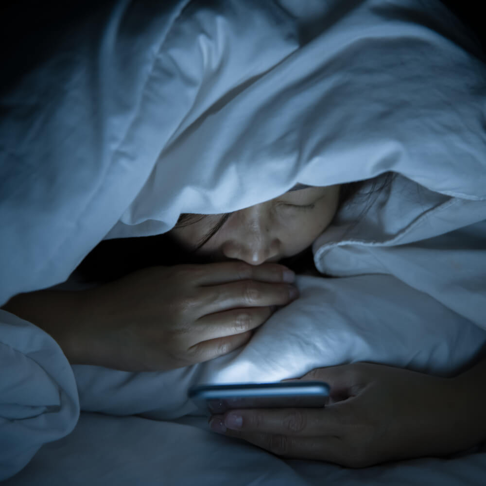 Eine Frau mit Smartphone im Bett
