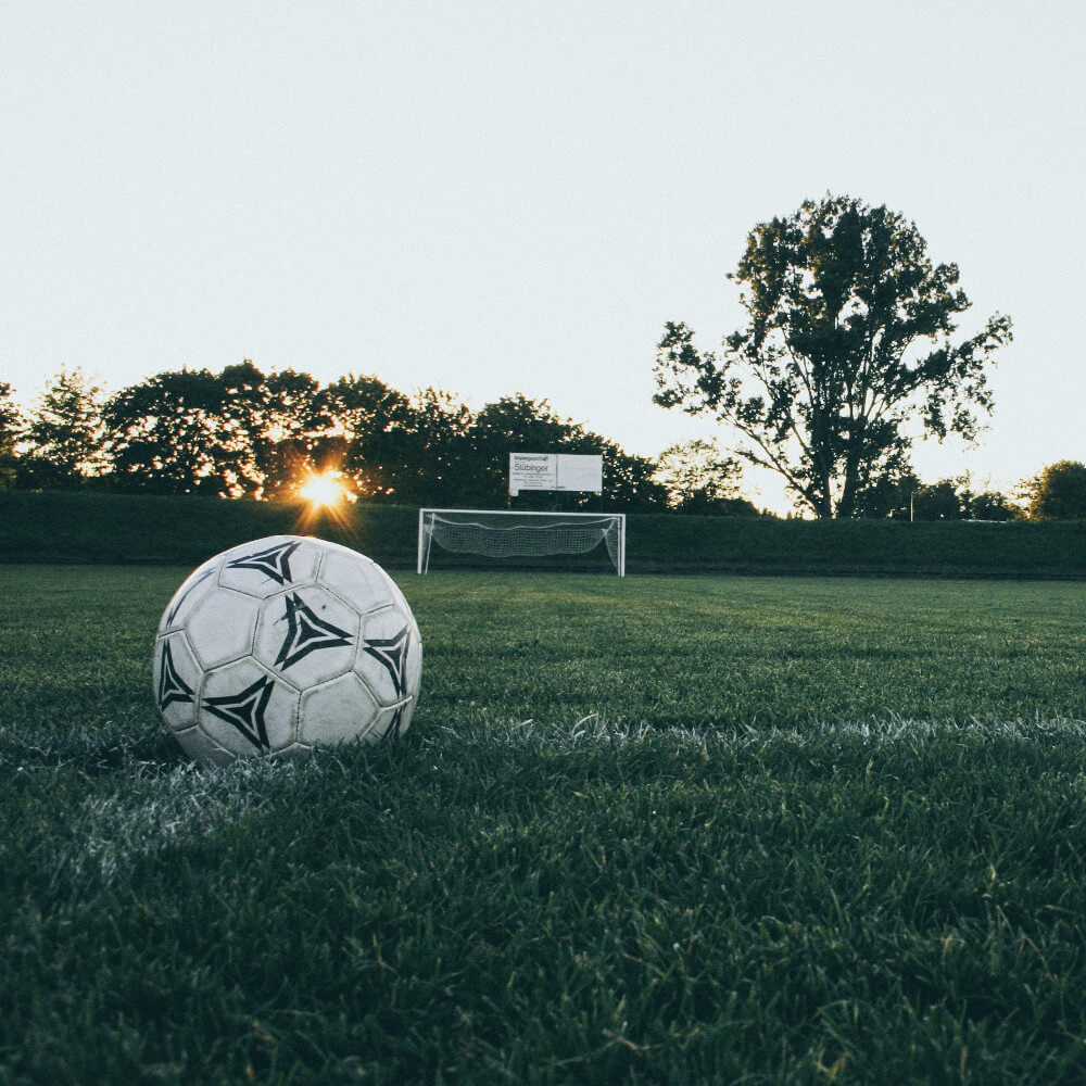 Ein Ball liegt auf dem Rasen. Titelbild für die besten Fußballpodcasts / Image by Markus Spiske via Pexels