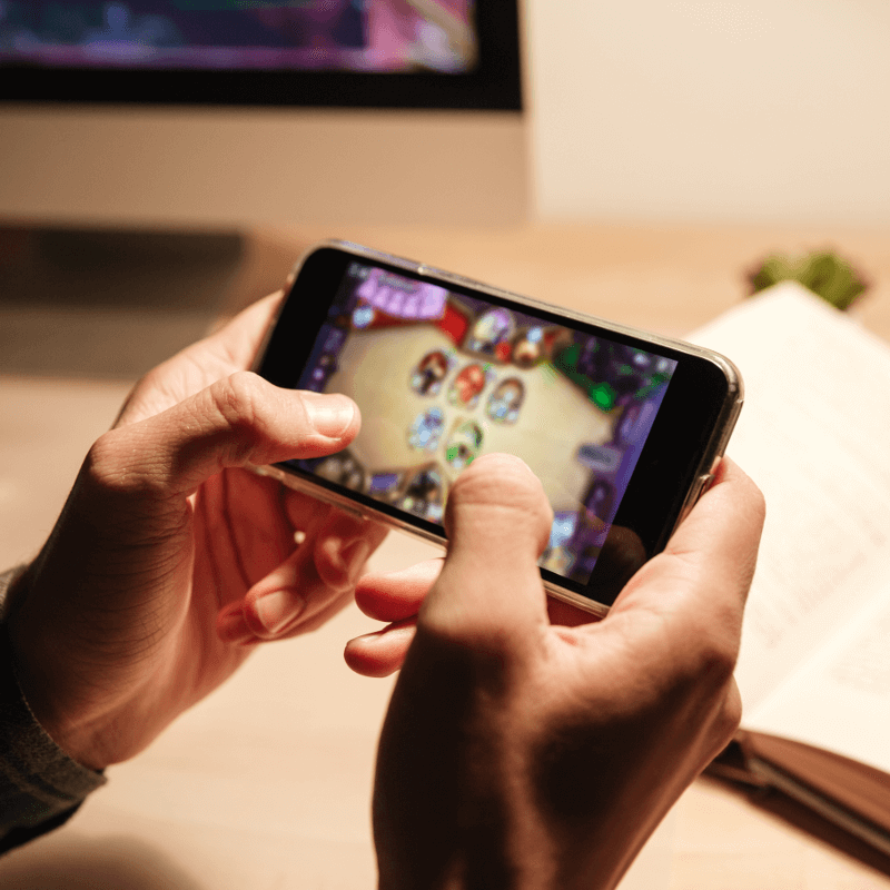 Hände halten ein Smartphone, auf dem ein Game geöffnet ist
