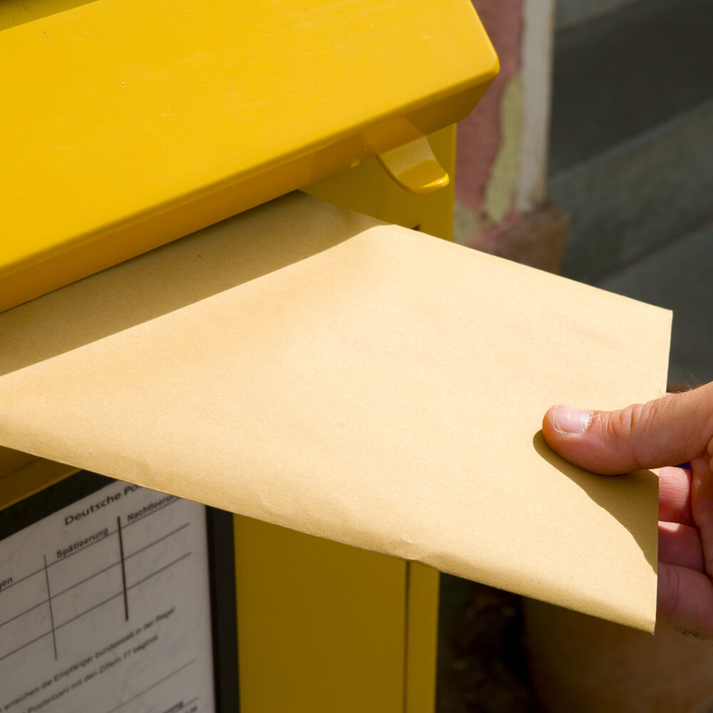 Einwurf eines Briefes in einen Briefkasten.