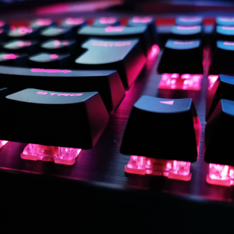 Nahaufnahme einer mechanischen Tastatur, dessen Tasten magentafarben beleuchtet werden.