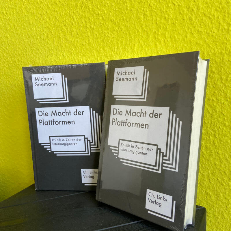 Zwei exemplare des Buches "Die Macht der Plattformen" vor gelben Hintergrund.