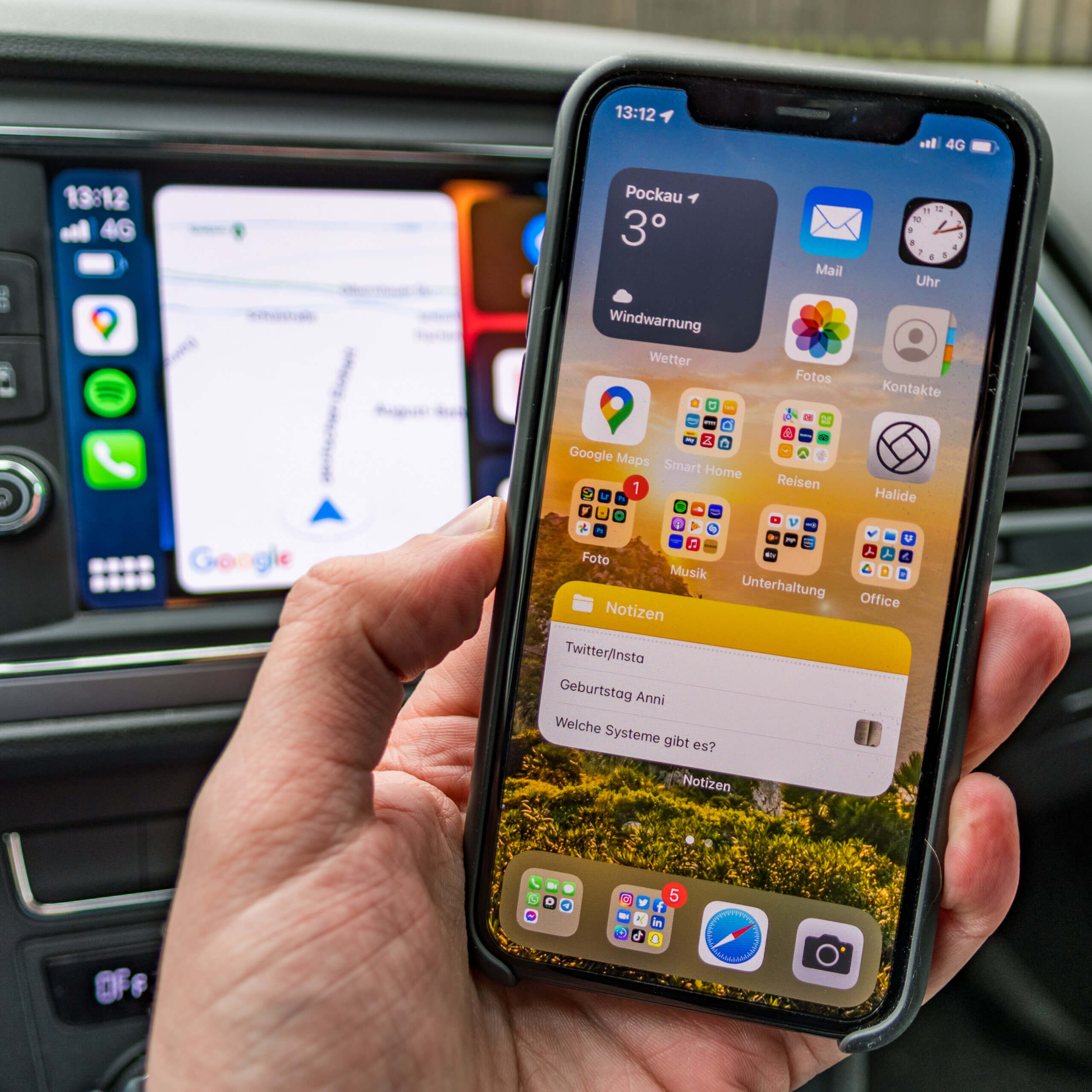 Das Smartphone in der Hand, das Infotainmentsystem auf dem Auto-Bildschirm.