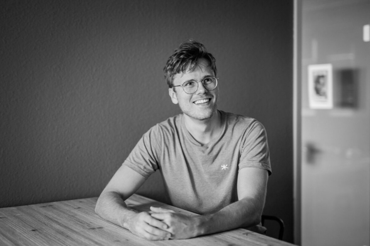 Jonas Thiemann an einem Tisch, er lächelt an der kamera vorbei