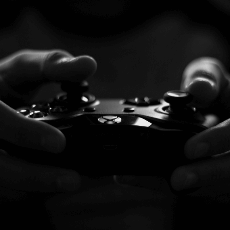 Titelbild zu "Was soll ich spielen?" zwei Händen halten einen XBox Controller - Schwarz weiß Foto von lalesh aldarwish von Pexels