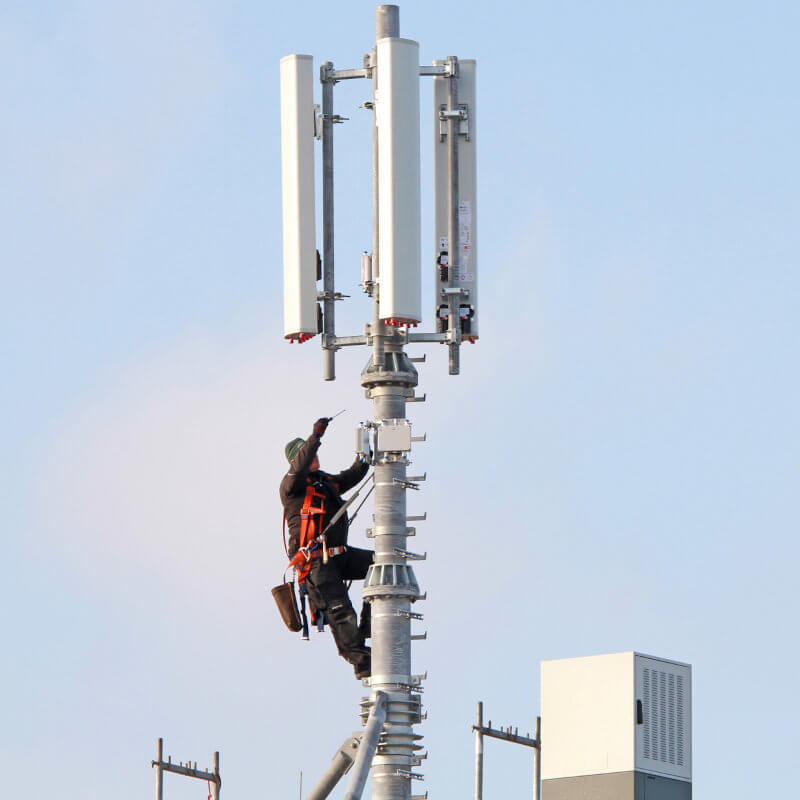 Ein Arbeiter in luftiger Höhe werkelt an einem Mobilfunkmast.