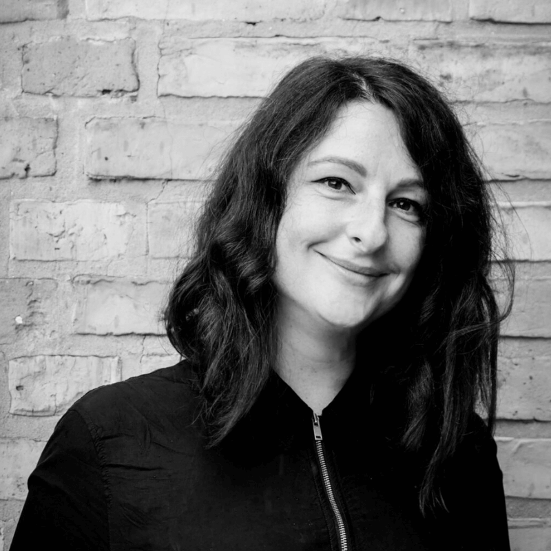 Anna Gleser im Portrait, sie trägt schwarz und lächelt schräg in die kamera