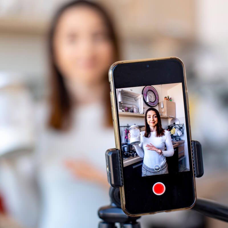 Eine junge Frau nimmt in ihrer Küche hochkant ein Video für Instagram auf