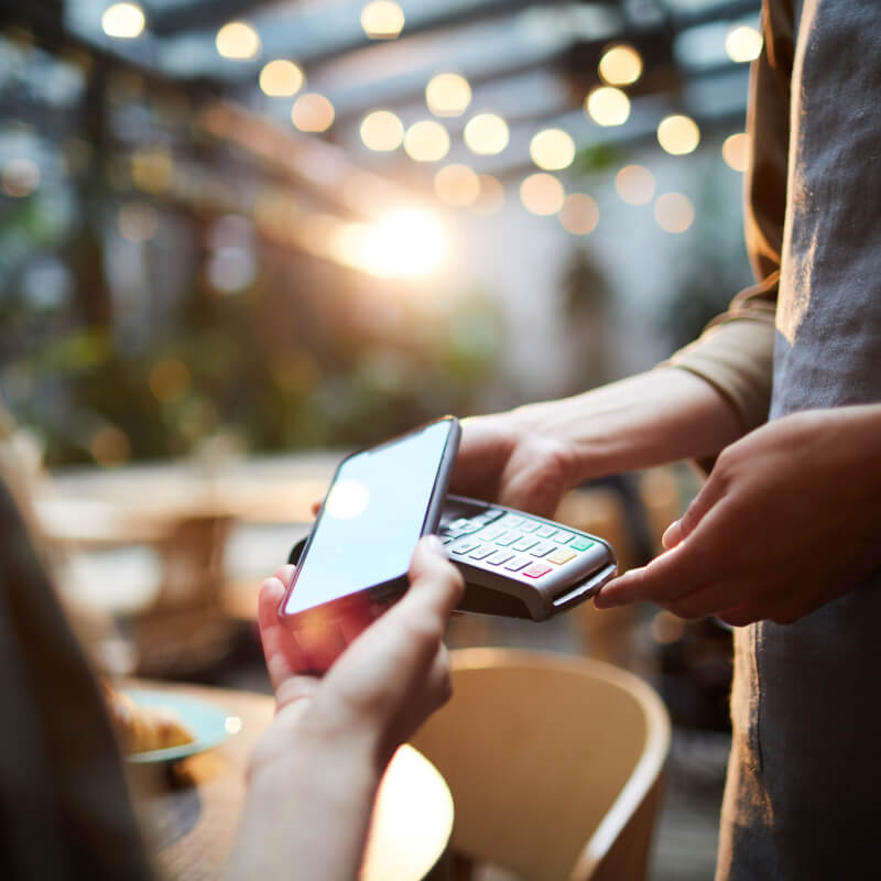 Beitragsbild Was ist NFC: Person tätigt eine NFC-Zahlung im Café