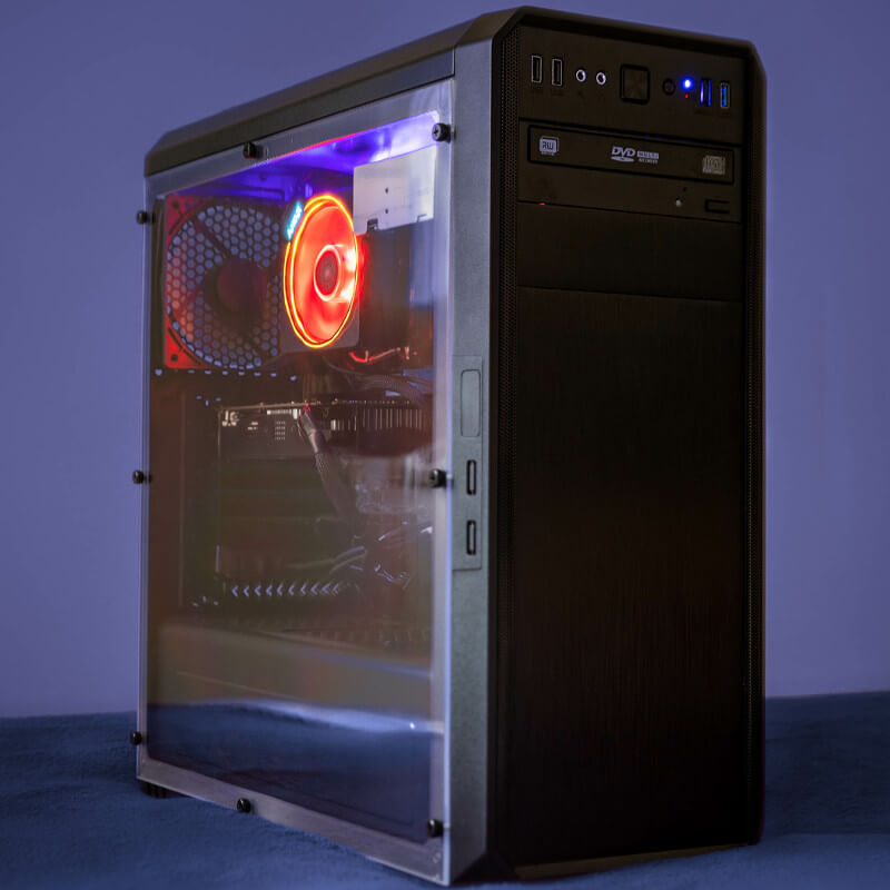 Ein PC vor dunkelblauen Hintergrund. Der PC hat eine durchsichtige Seite, wordurch man die Teils beleuchteten Komponenten sehen kann.