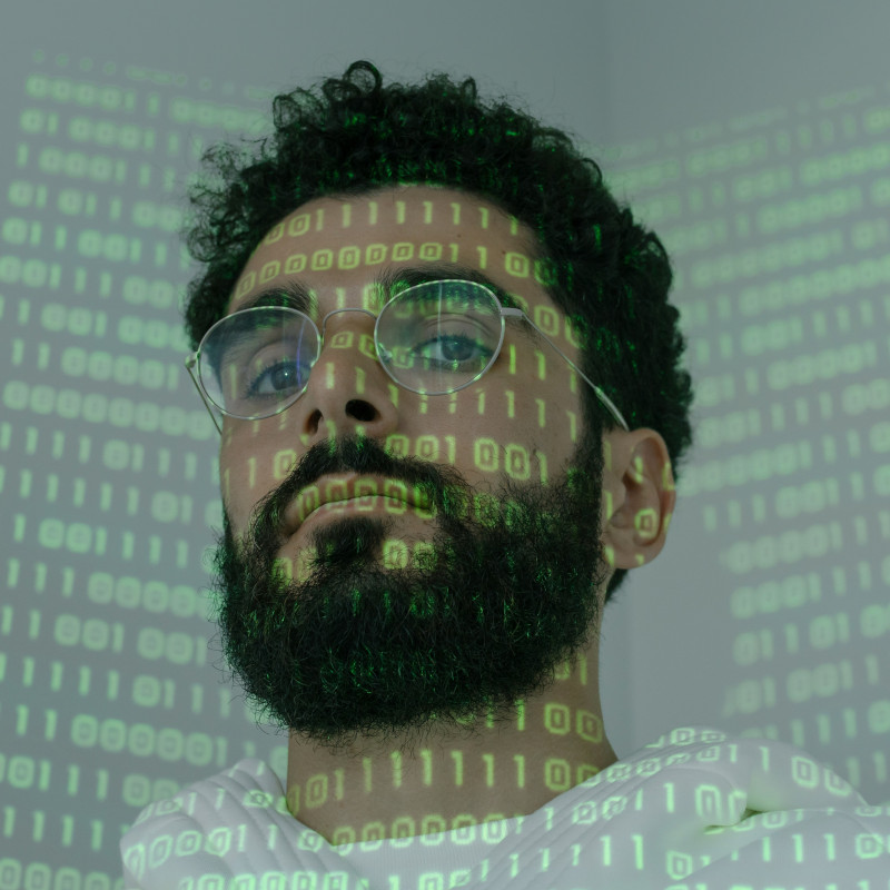 Mann mit Brille und grünem Binärcode, der auf ihn projiziert wird.
