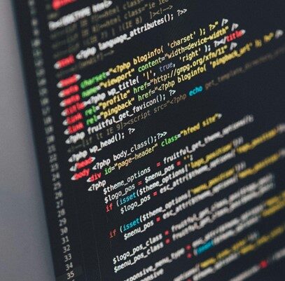 Das Bild zeigt einen Computerbildschirm mit farbigem Code, der vermutlich in einer Programmiersprache wie HTML, PHP oder JavaScript geschrieben ist. Der Code besteht aus verschiedenen Befehlen, Tags und Parametern, die in unterschiedlichen Farben angezeigt werden, um die Struktur zu verdeutlichen. Der Bildschirm wirkt dunkel, während der Code in leuchtenden Farben hervorsticht, was eine typische Arbeitsumgebung eines Programmierers oder Entwicklers darstellt.