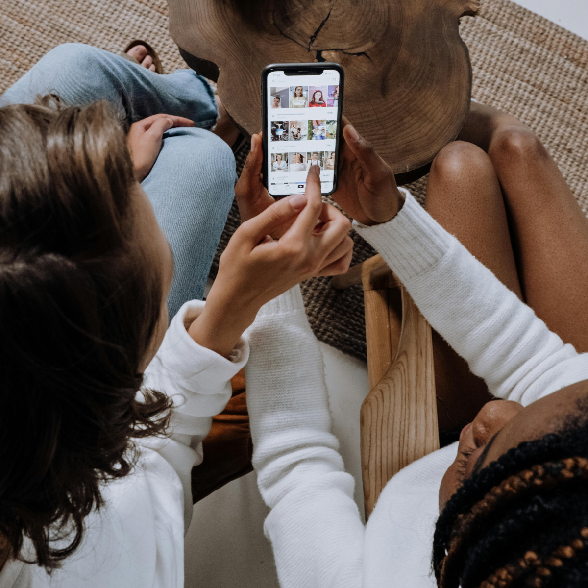 Zwei Freundinnen schauen sich auf einem Smartphone TikTok-Videos an.