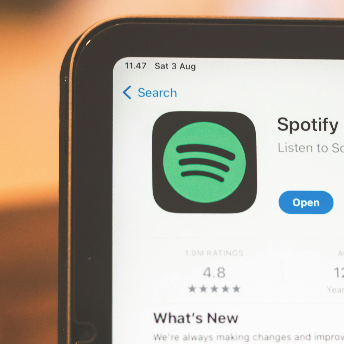Zu sehen ist die obere Ecke eines Laptops. Geöffnet ist der Appstore mit der Spotify-App. am unteren Rand steht geschrieben "What's New?"