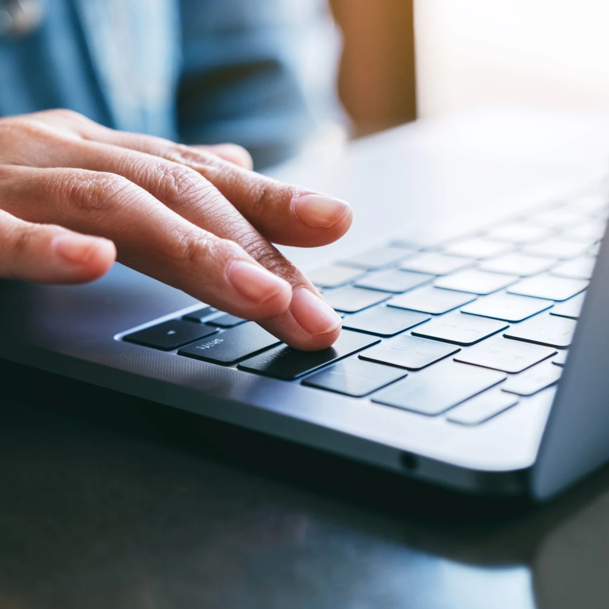 Hand bestätigt eine Eingabe auf der Tastatur eines Laptops per Enter-Taste.